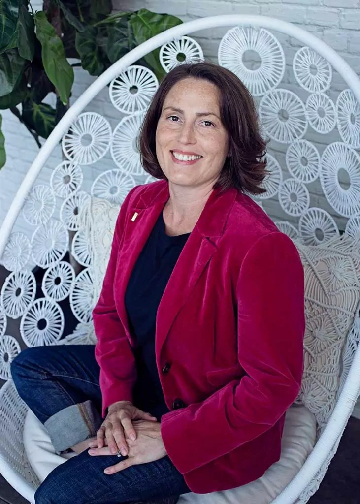 Smiling person in red jacket on white chair.